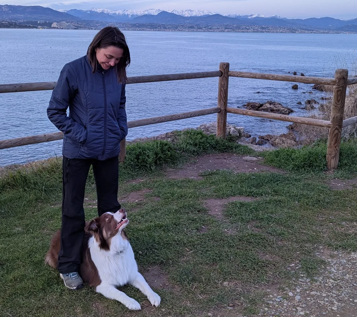 Femme avec un chien devant un paysage de lac et montagne